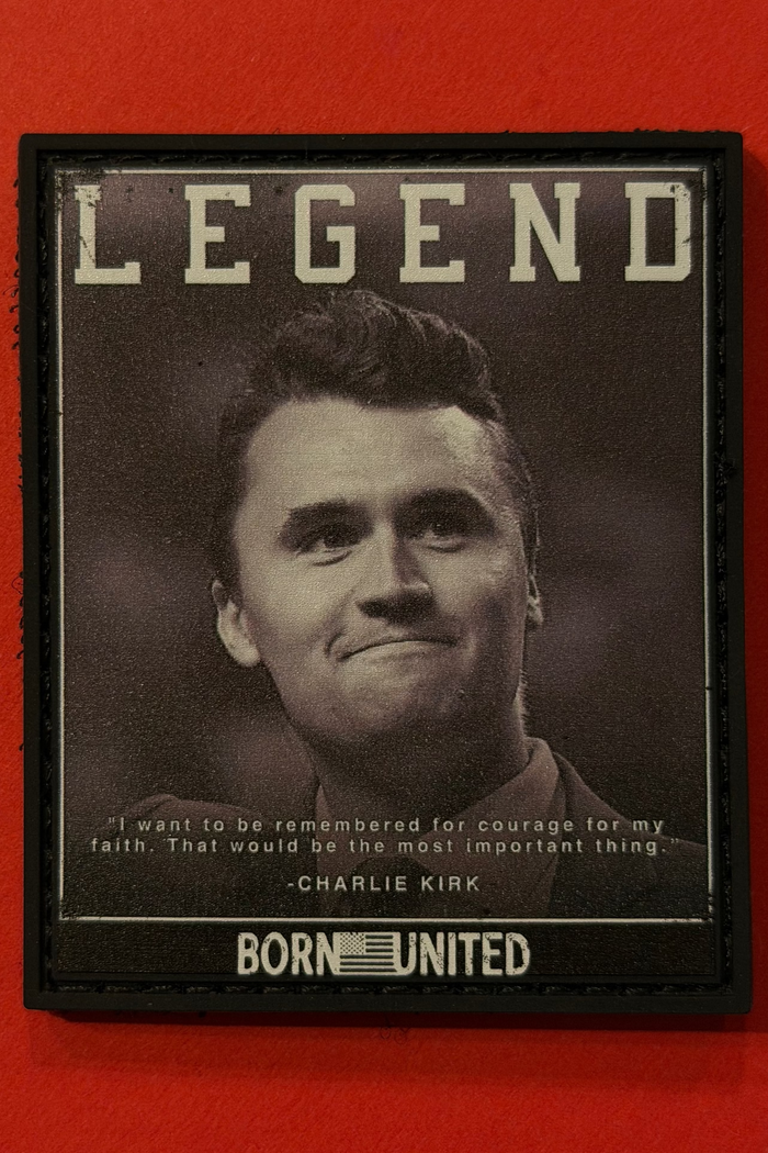 A black and white photo of a man with "LEGEND" above, featuring a quote from Charlie Kirk: "I want to be remembered for courage, for my faith. That would be the most important thing." Product: Legend - Charlie Kirk PVC Patch by Born United Private Label.