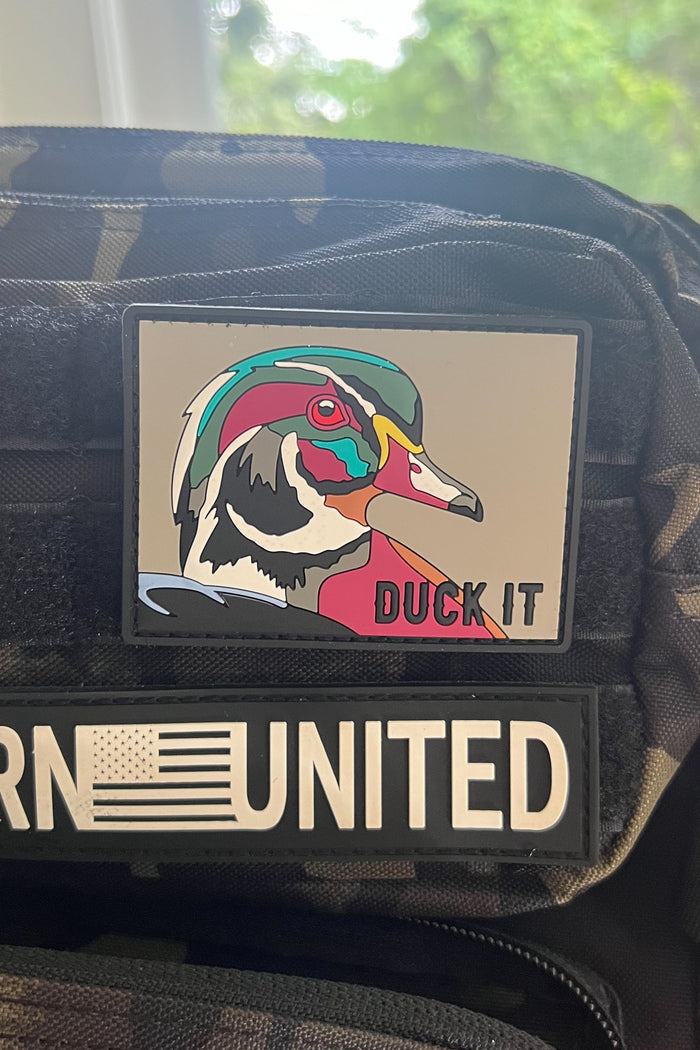 Patch with a colorful duck design and 'Duck It' text on a tactical vest.