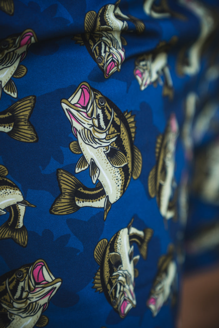 Close-up of blue fabric with large, detailed fish in brown, white, and pink on the Mucker Bucket Men's Performance Athletic Shorts | 5.5"- Big Bass Daddy adds a lively, dynamic touch to these versatile shorts.