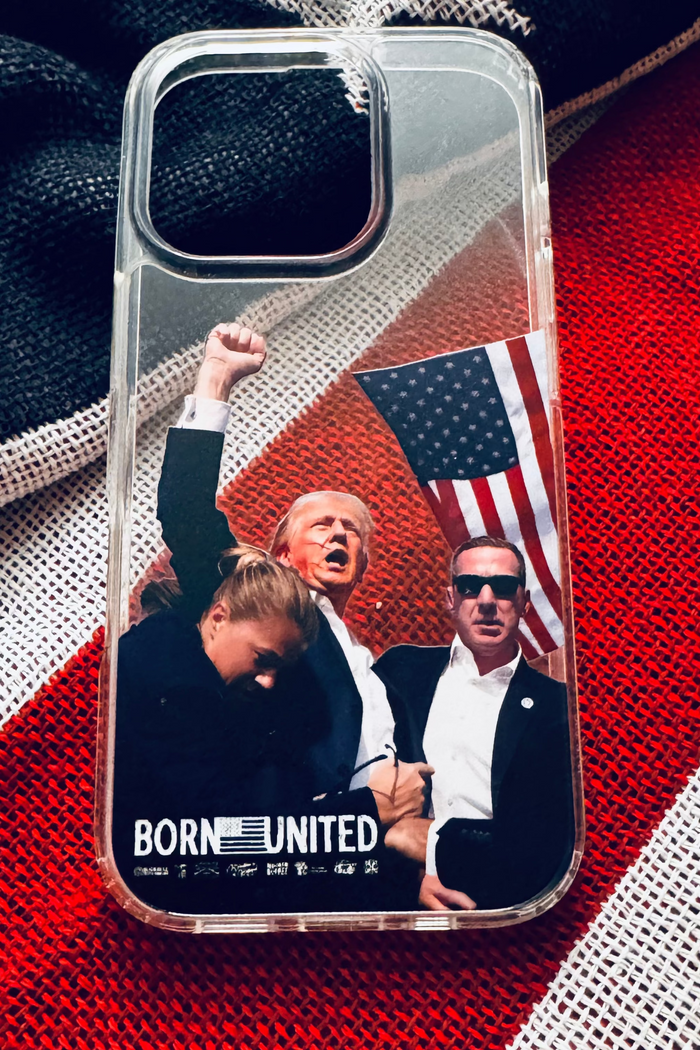 The Forever Legend iPhone Case by Born United Private Label showcases Donald Trump raising his fist, a woman bowing her head, a man in sunglasses, and a U.S. flag, with “BORN UNITED” boldly printed at the bottom.