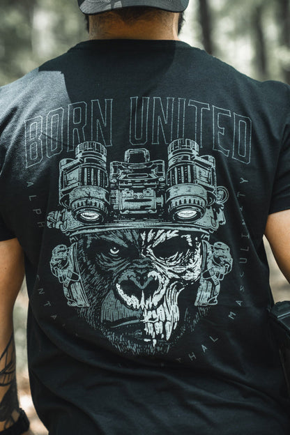 A man outdoors, seen from behind, wears the Alpha Mentality shirt by Born United Private Label—a bold black tee with a fierce gorilla in night-vision goggles and “BORN UNITED” above, embodying confidence and strength.