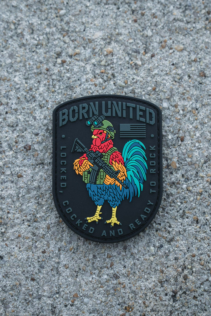 The Battle Bird PVC Patch by Born United Private Label shows a vibrant rooster in a helmet with a rifle. It reads "BORN UNITED" on top and "LOCKED, COCKED AND READY TO ROCK" below, all set against a rough concrete backdrop.