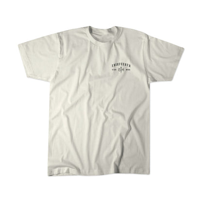 A premium plain white tee from 13th, the Be Strong Premium Tee features minimalist black text and numbers printed on the left chest that read “Thirteenth” and “13th,” along with a short line of smaller text subtly inspired by Joshua 1:9.