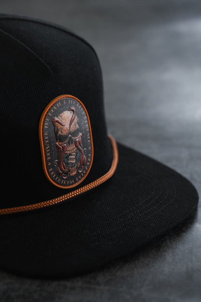Between The Devil & Deep Blue Sea Snapback by Relentless Betrayal—a black cap featuring an orange-trimmed patch with a fierce skull and tentacles, set against a dark, textured background; this bold nautical snapback makes a striking statement in pirate-inspired style.
