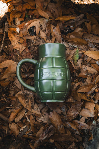 The BU Sip Sip Boom Mug by Born United Private Label is a green grenade-shaped mug with “BORN UNITED” embossed, set among dry leaves—a bold conversation starter for your collection.