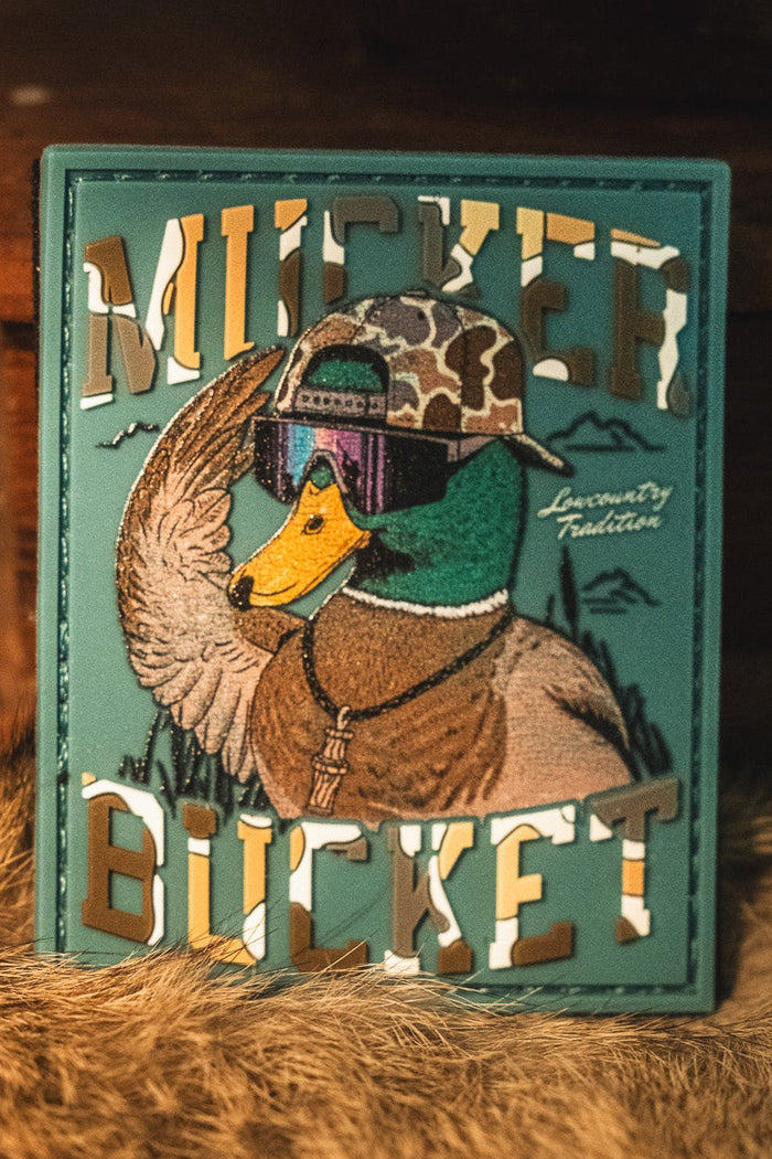 Show off your style with the Cool Duck PVC Patch by Mucker Bucket—a striking 4x4 patch showcasing a duck in a camo cap and sunglasses, with "MUCKER BUCKET" boldly displayed. This 3D PVC patch features Velcro backing for effortless attachment to your favorite gear.