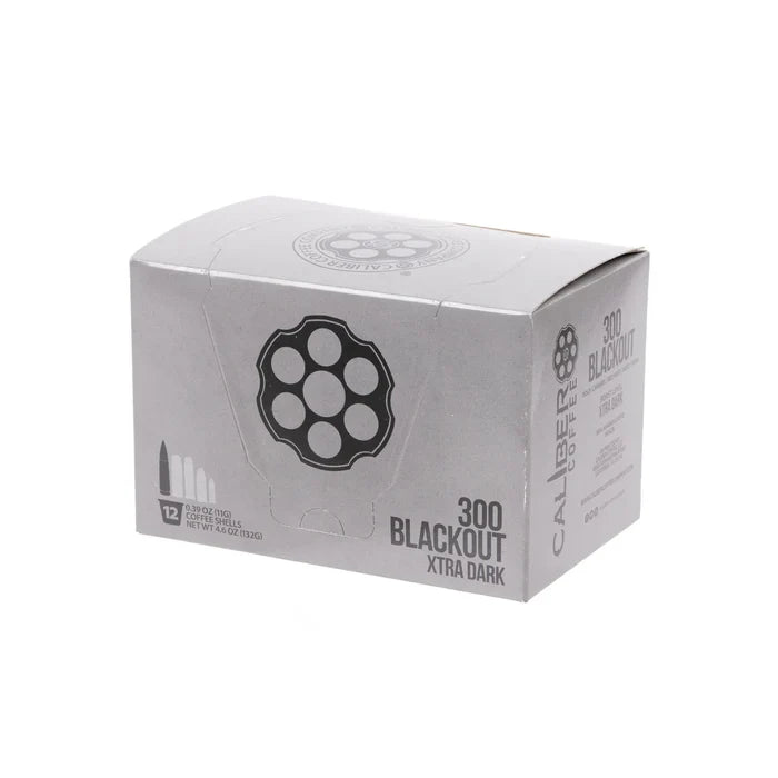 A silver box labeled Dark Roast 300 Blackout Single-Serve Shells by Caliber Coffee Company, featuring bullet and revolver cylinder illustrations. Contains 12 servings of specialty dark roast coffee, totaling 4.9 ounces (139.2 grams).