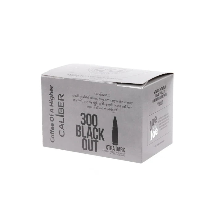 A gray rectangular box of specialty grade coffee from Caliber Coffee Company is labeled Dark Roast 300 Blackout Single-Serve Shells. The design mimics ammo packaging with Coffee of a Higher Caliber text, plus rights protection and logo details on the side.