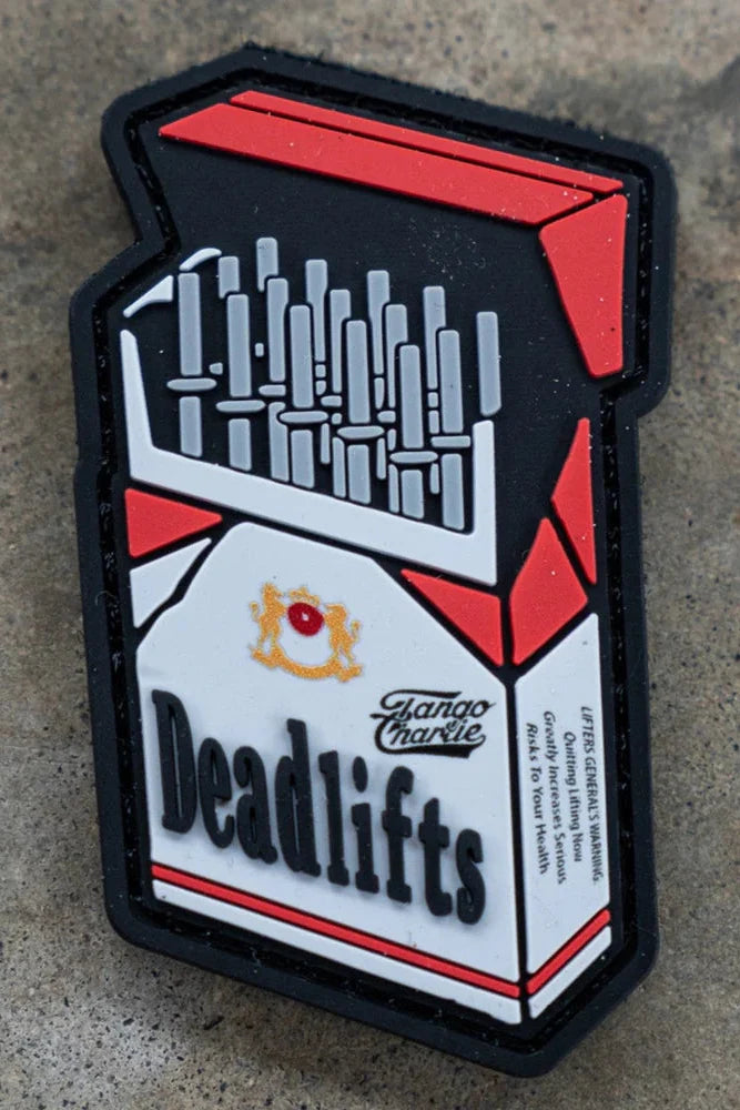 The Deadlift PVC Patch by Tango Charlie Apparel is shaped like a cigarette pack, but with barbells inside and Deadlifts boldly labeled on a concrete-style background.