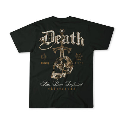 The Death's Defeat Premium Tee by 13th features a gothic design with "Death," a large cross, skull details, and Isaiah 25:8. Stylized text includes "Has Been Defeated" and "thirteenth," sharing a message of spiritual hope.