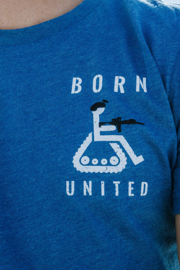 A person is wearing the Disabled Vet - Blue t-shirt by Born United Private Label, showcasing a disgruntled wheelchair symbol with tank tracks and a figure with a rifle, along with the words BORN and UNITED boldly printed above and below.