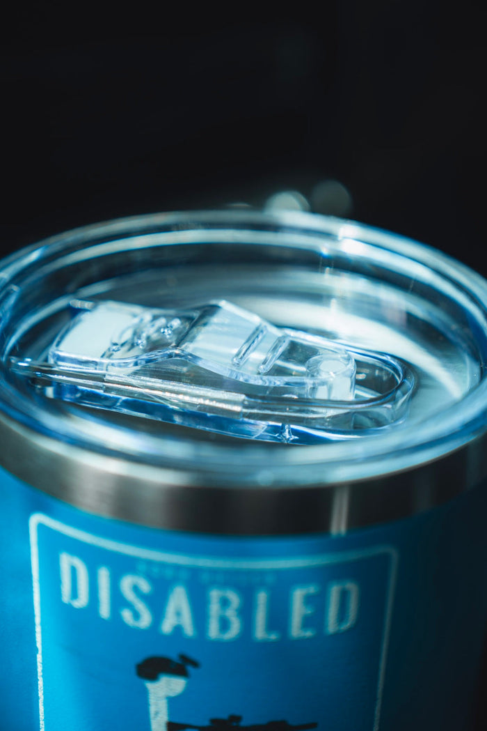 A close-up of the Born United Private Label Disabled Vet Tumbler - 20oz in blue with a clear plastic lid. The label reads "DISABLED," making it a meaningful gift for disabled veterans. The photo focuses on the tumbler's top.