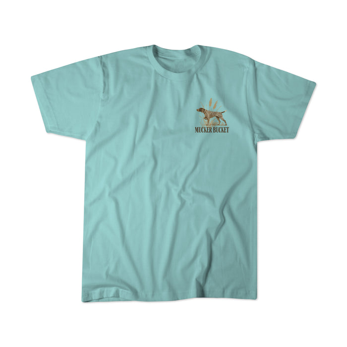 A light blue, ring-spun cotton t-shirt from Mucker Bucket featuring a small graphic of a dog and the text "Dog DNA Premium Tee" on the left chest area.
