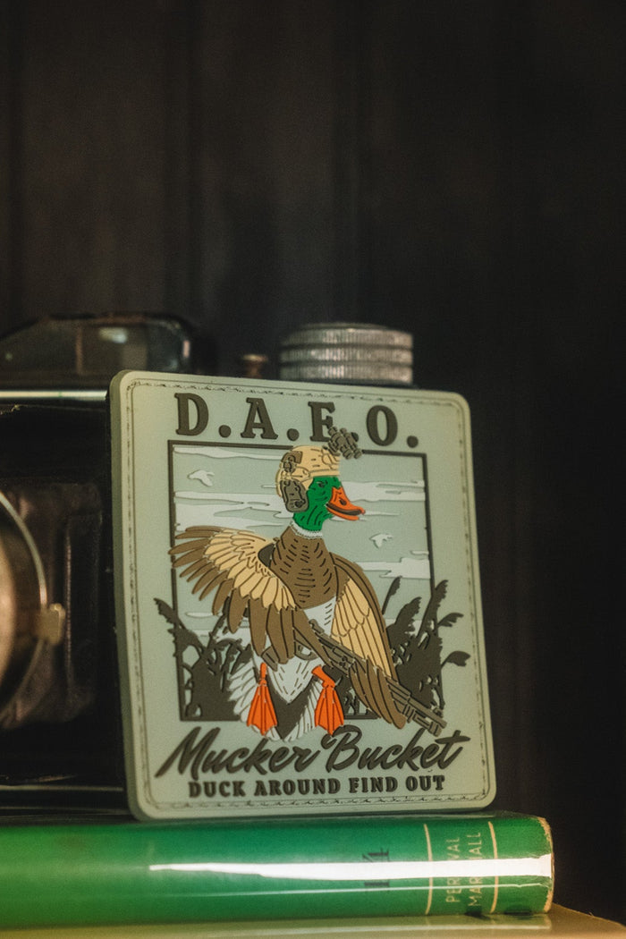 A vintage-style metal flask with a duck illustration and the text 'D.A.