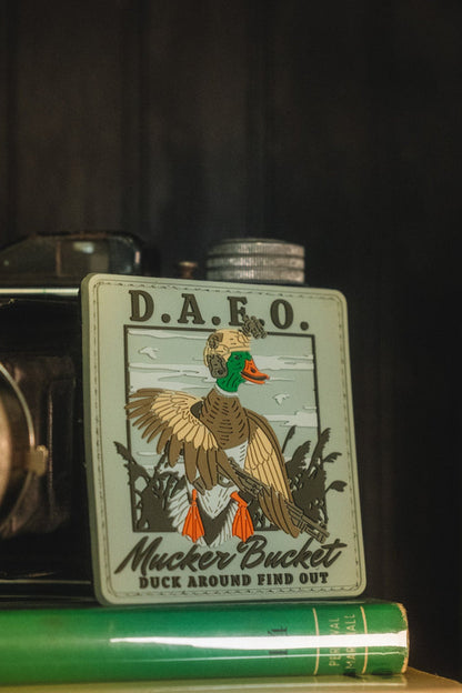 A vintage-style metal flask with a duck illustration and the text 'D.A.