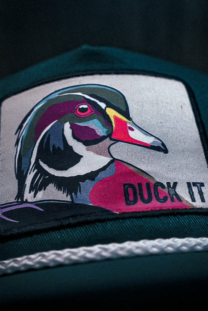 The Mucker Bucket Duck It - OG Green Wood Duck bucket hat features a handmade design with a high-quality embroidered patch of a colorful duck and DUCK IT, complemented by a white braided rope above the brim.