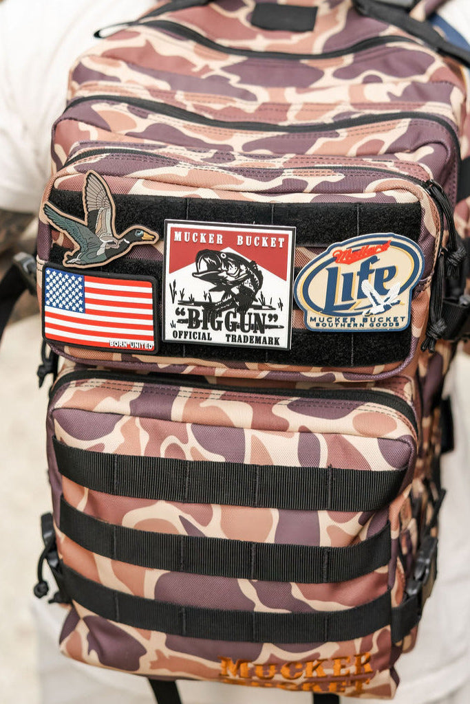 Camouflage backpack with various patches on a blurred background
