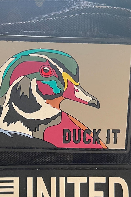 Colorful duck patch with 'DUCK IT' text on a textured surface