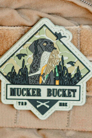 Patch with a dog and owl design on a beige background, featuring the text 'Mucker Bucket'.