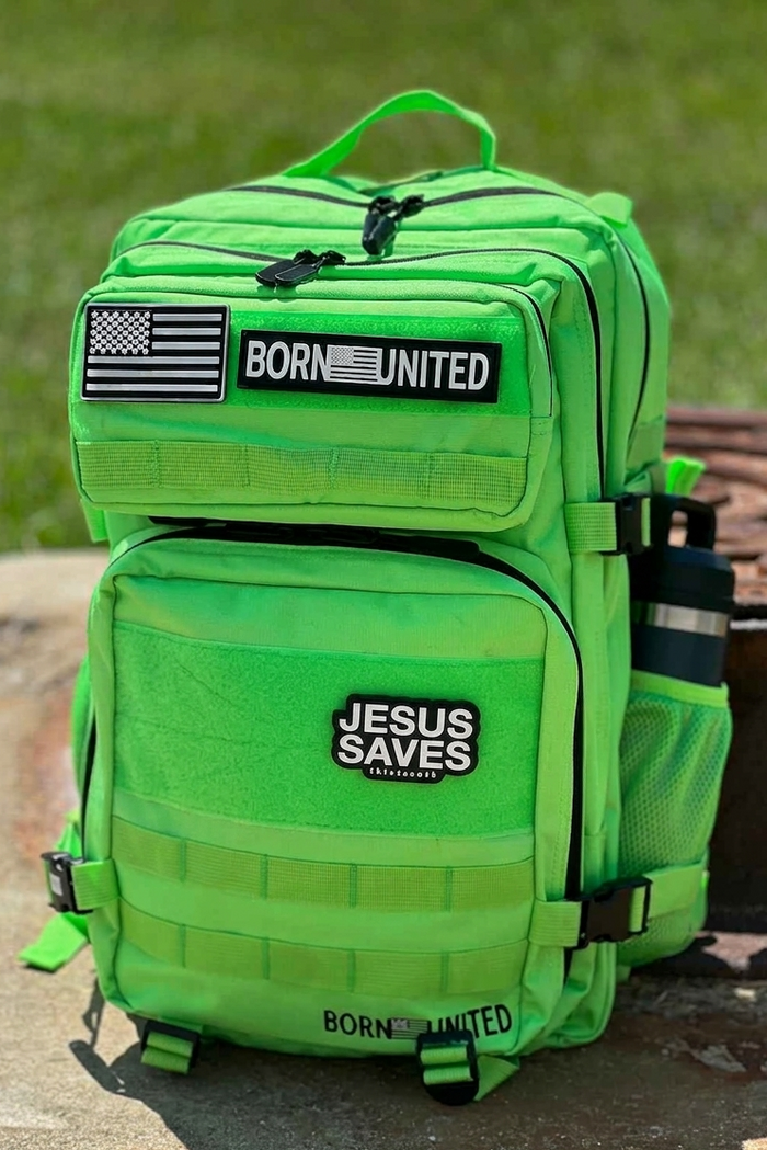 A Key Lime Premium Tac-Pac - 45L by Born United Private Label sits on concrete with grass behind it. The backpack features "BORN UNITED," an American flag, and "JESUS SAVES" patches, plus a water bottle in the side pocket.
