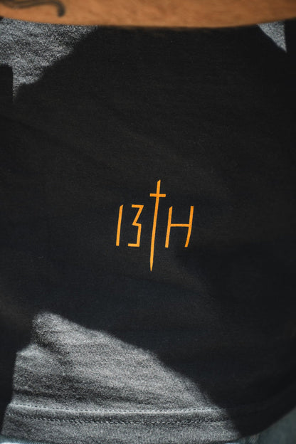 Black shirt with '13th' logo in orange on a textured surface