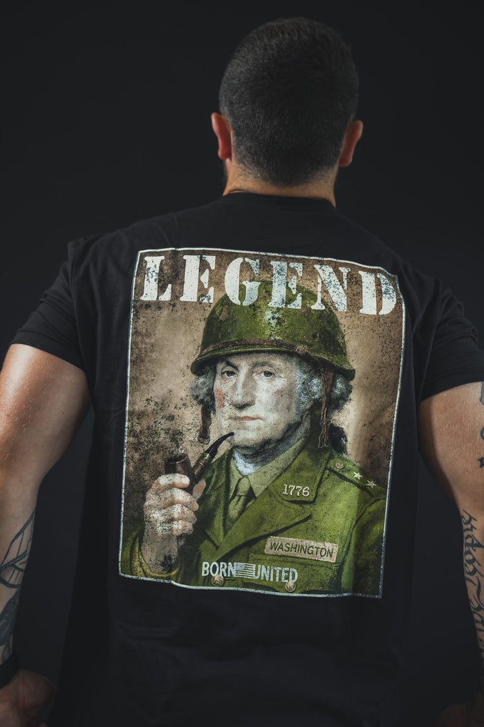 A tattooed man faces away, wearing the Born United Private Label "Legend - Washington" tee, which shows George Washington in military attire, smoking a pipe with "LEGEND" above—perfect for history fans.