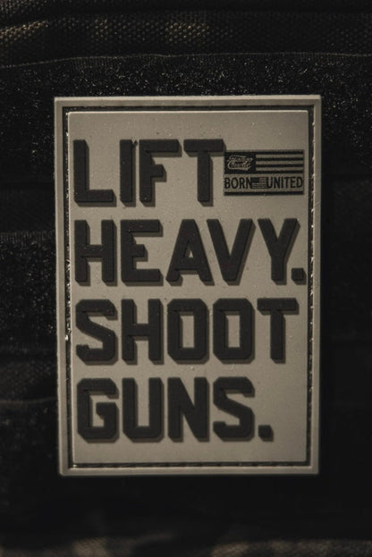 The LHSG - Patch by Tango Charlie Apparel is a rectangular 3D PVC Velcro patch with bold black "LIFT HEAVY. SHOOT GUNS." text, a small American flag, and "BORN UNITED." in the top right corner.