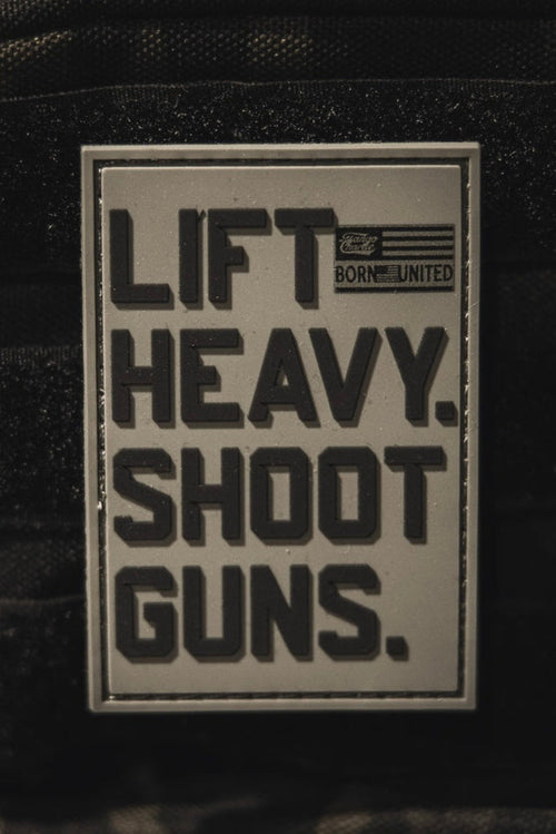 The LHSG - Patch by Tango Charlie Apparel is a rectangular 3D PVC Velcro patch with bold black "LIFT HEAVY. SHOOT GUNS." text, a small American flag, and "BORN UNITED." in the top right corner.