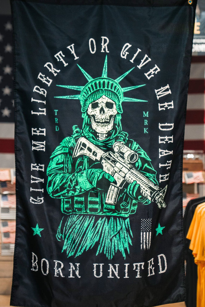 The Liberty or Death Flag by Born United Private Label features a skeleton Statue of Liberty with a rifle and the phrases "Give me liberty or give me death" and "Born United" on a dark background, inspired by American revolutionary flags.