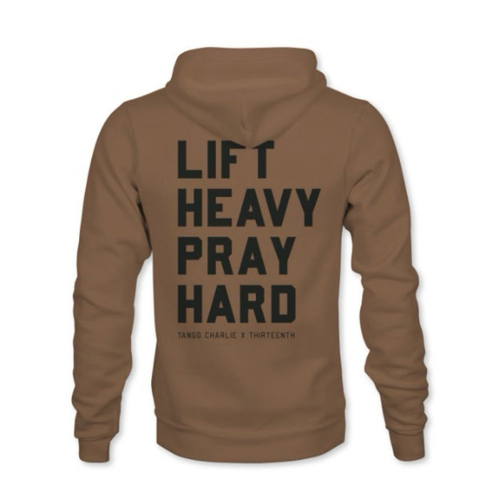 A brown hoodie from Tango Charlie Apparel, featuring "LIFT HEAVY. PRAY HARD." in bold black text on the back, with "TANGO CHARLIE X THIRTEENTH" below. Made from a comfy cotton-poly blend.
