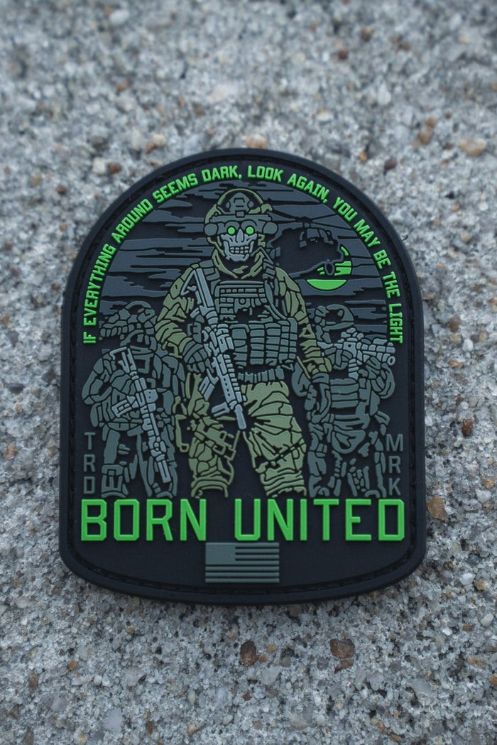 The Light in the Darkness PVC Patch by Born United Private Label features four armed soldiers with night vision gear on gravel, the quote "If everything around seems dark, look again, you may be the light," and "Born United" below.