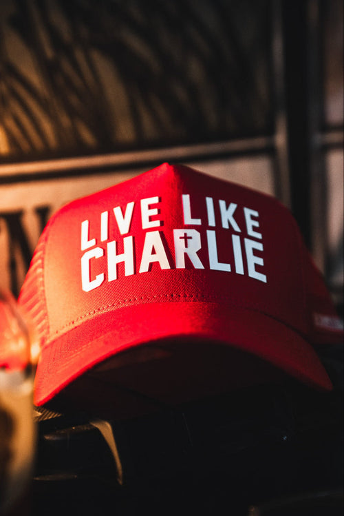 The Born United Private Label Live Like Charlie Trucker Snapback features a red curved brim and bold white LIVE LIKE CHARLIE text with a cross-styled T—handmade and perfect for any fan.