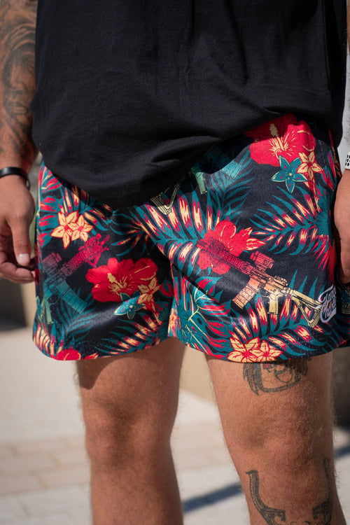 Person wearing colorful floral shorts with a black top, standing outdoors.