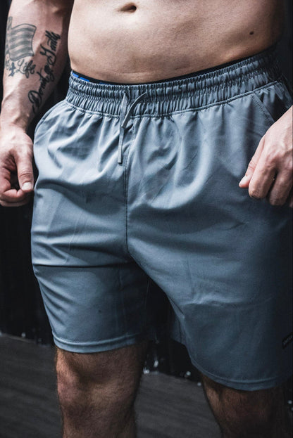 Person wearing light blue shorts with a dark background