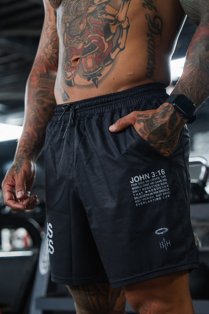 Person wearing black shorts with tattoos visible in a gym setting
