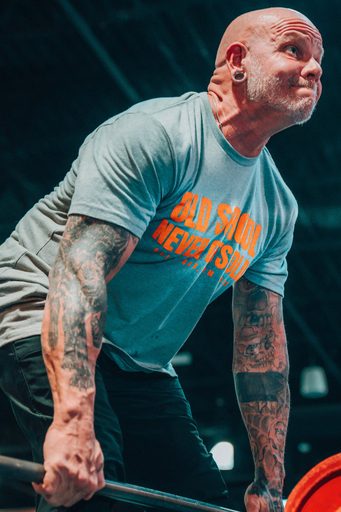 Man lifting weights with a focus on his upper body and tattoos.