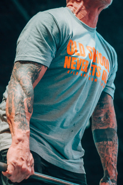 Person wearing a gray t-shirt with orange text, holding a barbell.