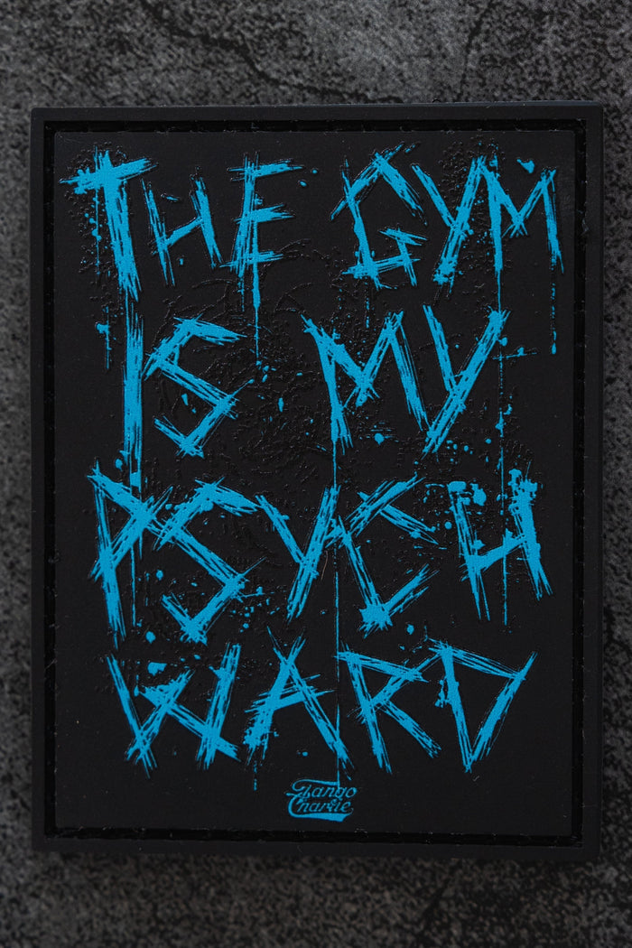 The Psych Ward - Patch by Tango Charlie Apparel is a black rectangular 3D PVC patch with distressed blue "THE GYM IS MY PSYCH WARD" text, shown on a textured gray surface.