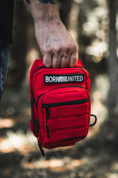 A person holds the Red Reaper Tactical Sling-Pac (4L) by Born United Private Label, featuring multiple zippered compartments and a signature patch—ideal for concealed carry or use as a compact tactical sling bag outdoors.