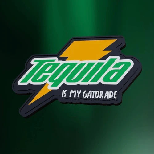 A vibrant PVC patch from Tango Charlie Apparel, called “Tequila,” features a yellow lightning bolt and green text reading Tequila is my Gatorade on a dark green gradient background, and comes with velcro backing for easy attachment.