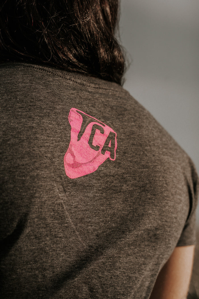 A person wears the charcoal THICC Boys Fan Club Crop Tee by Tango Charlie Apparel, featuring a pink "TCA" graphic on the upper back—ideal for any Thicc Boys Fan Club member.