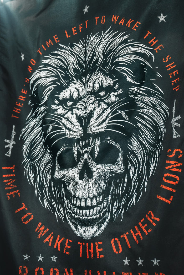 The Born United Private Label Waking Lions Flag features a black design with a white lion-skull face and bold red text: “THERE'S NO TIME LEFT TO WAKE THE SHEEP. IT'S TIME TO WAKE THE OTHER LIONS.” Made of durable polyester.