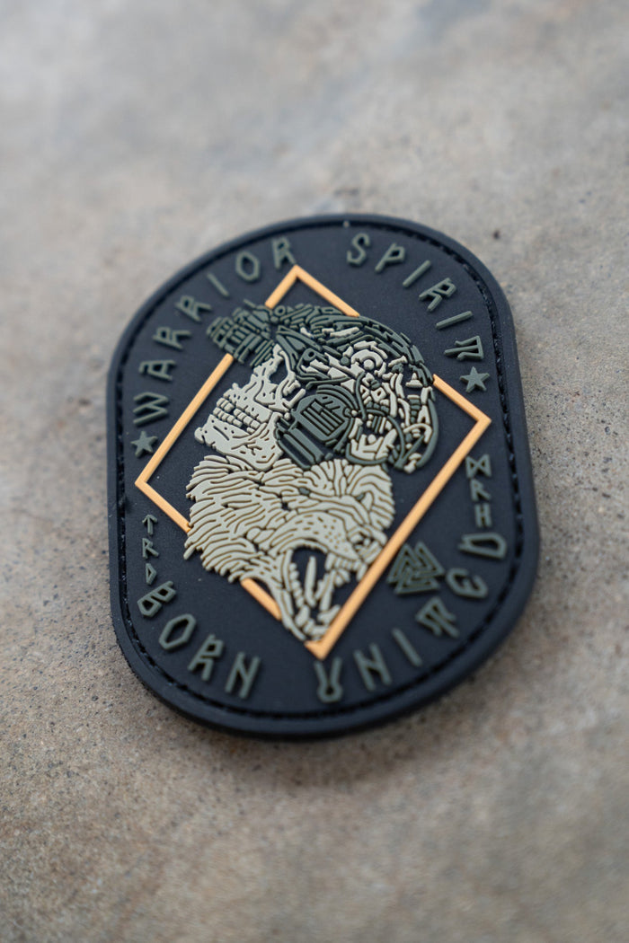The Warrior Spirit PVC Patch by Born United Private Label features a black and gold skull with night vision goggles and wolf fur, encircled by “WARRIOR SPIRIT” and “BORN UNBROKEN” in a circular design.
