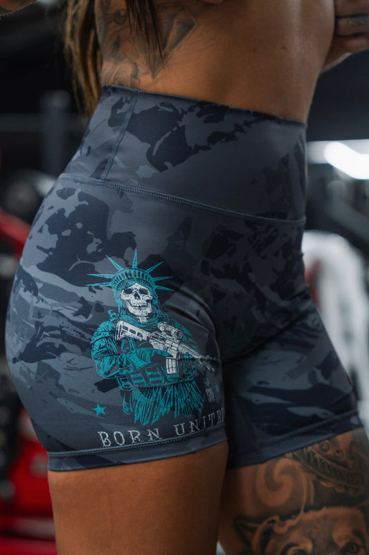A woman wears Born United Private Label's Liberty or Death high-waisted seamless front compression training shorts, featuring the Statue of Liberty as a skeleton with a rifle and "BORN UNITED" text below.